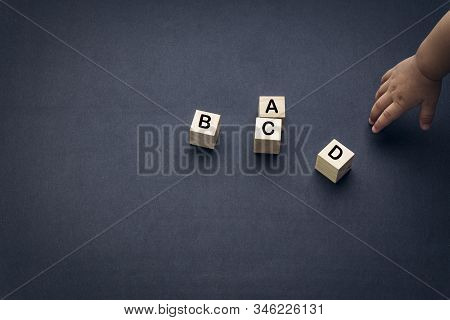 Wooden Alphabet Cube With Words Abcd Closeup And Children Hands On Black Background. Selective Focus