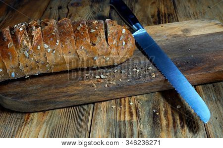 Closeup View.  Sliced ​​brown Bread Lies On A Wooden Cutting Board.