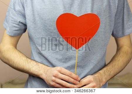 Valentine's Day Concept Valentine's Day. Men's Hands Hold A Red Heart On A White Wooden Background. 