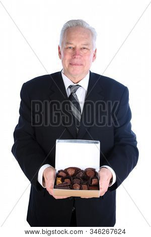Valentines Day. Man in a suit holds a box of assorted exotic chocolates. Isolated on white. Room for text. Clipping Path. People world wide love chocolates. Chocolate is enjoyed for holidays. 