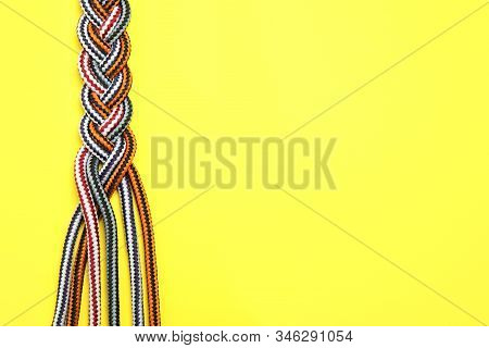 Top View Of Braided Colorful Ropes On Yellow Background, Space For Text. Unity Concept