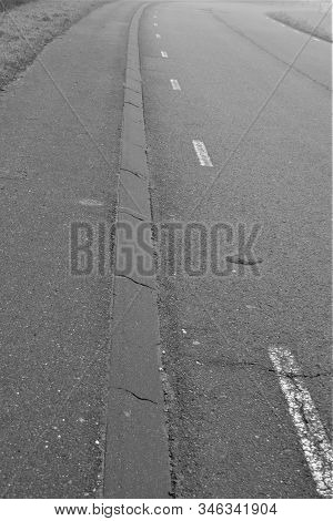 Road With White Stripes And Curbstone In Black And White