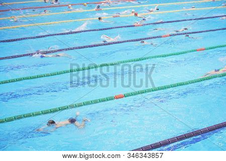 Indoor Big Sport Swimming Pool. Lots Of Children Swimming Along Multiple Lanes. Healthy Active Lifes
