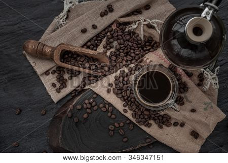 Coffee Style, Cup Of Coffee And Coffee Beans Roating With Old Wooden Scoop And Coffee Beans Around O