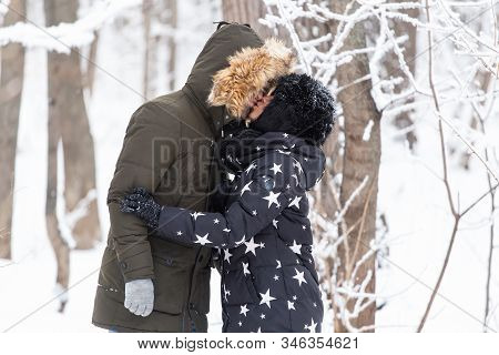 Young Love Couplekissing In A Snowy Park. Winter Season.
