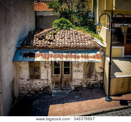 Dilapidated House With Broken Tile Roof Nestled Between 3 Buildings In Eressos On The Island Of Lesv