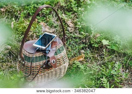 Mock Up Of A Smartphone With Charging Power Bank On A Basket In The Forest. Concept On The Theme Of 