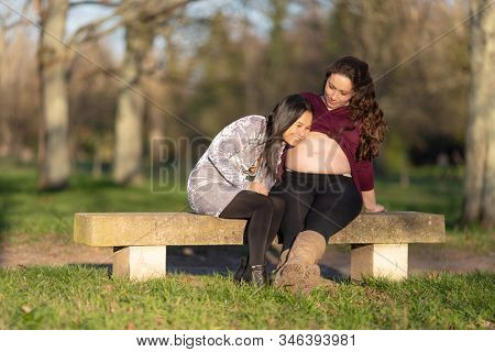 Woman listening the sign of foetus life in the belly of her pregnant friend.