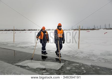 Workers Rafting Ice Blocks Along A Channel Cut Out By A Frozen Lake