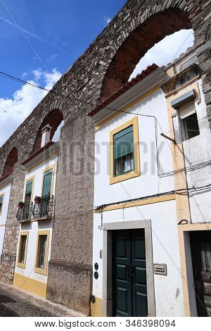 Evora Town In Portugal. Unesco World Heritage Site. Prata Aqueduct With Homes Beneath Arches.