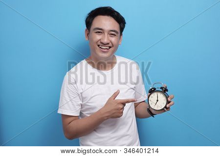Young Asian Man Wearing Shite Shirt Shows Time On Clock With A Happy Expression, Time Management. Ha