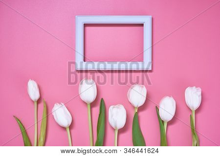 Light Wooden Frame With Many White Tulips Are On The Pink Background. Top View, Copy Space