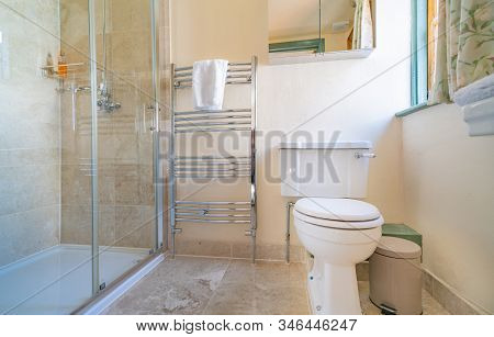 Modern Bathroom  With Glass Shower, Chrome Towel Rail And Tiled Floor.