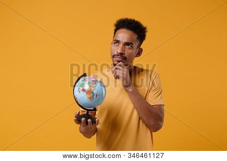 Pensive Young African American Guy In Casual T-shirt Posing Isolated On Yellow Orange Background In 