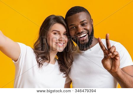 Selfie Fun. Cheerful Interrational Couple Taking Self-portrait Together, Looking At Camera And Smili