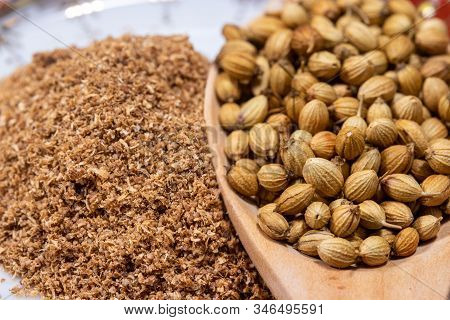 Close-up Of Dried Coriander Seeds In A Spoon With Coriander Powder Background, Indian Cuisine Herbs.