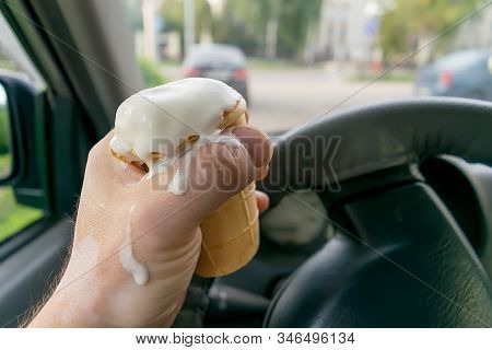The Driver Holds The Ice Cream While Driving A Car