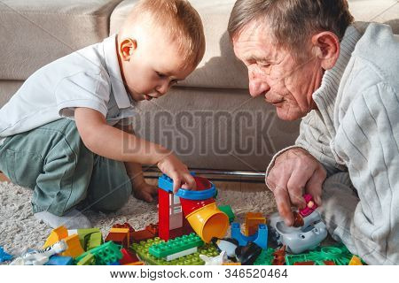 Elderly Grandpa Or Grandfather Plays With His Little Grandson