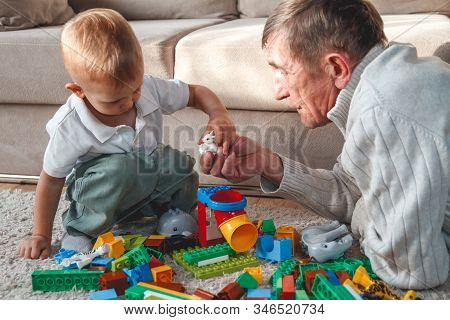 Elderly Grandpa Or Grandfather Plays With His Little Grandson