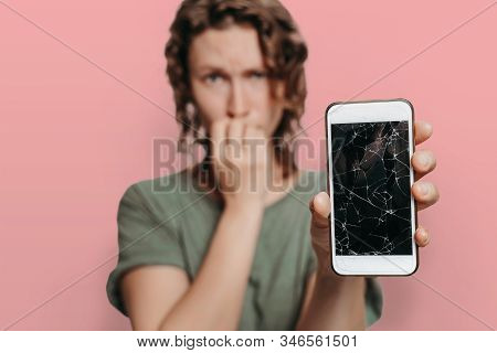 Sad Unhappy Girl Bites Nails While Holding Her Broken Smartphone With Cracked Display, Isolated On P