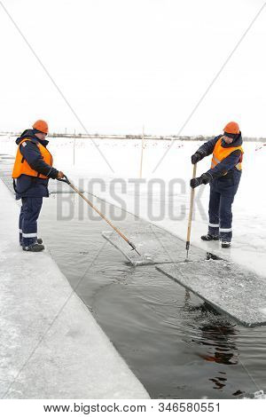 Workers Rafting Ice Blocks Along A Channel Cut Out By A Frozen Lake