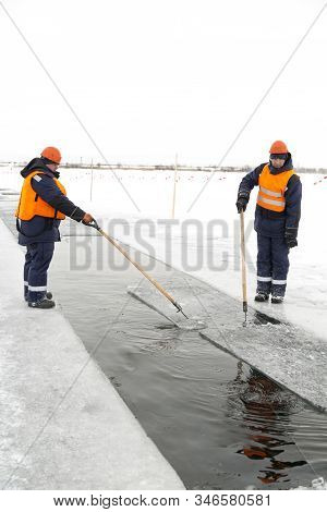 Workers Rafting Ice Blocks Along A Channel Cut Out By A Frozen Lake