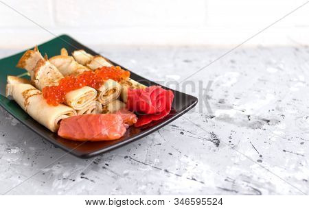 Pancakes Twisted Into A Tube With Red Fish, Red Caviar And Ginger On A Concrete Background