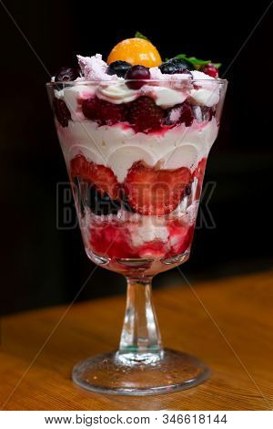Colorful Trifle Dessert With Fizalis, Strawberries, Blueberries, Jam And Whipped Cream On High Trans