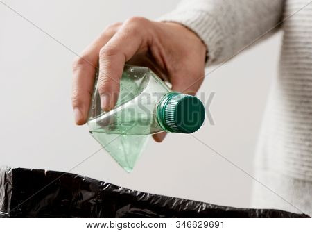 closeup of a young caucasian man about to throw an empty plastic bottle to the trash bin