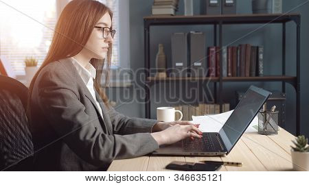 Side View Of Busy Businesswoman Working On Laptop Typing Something On Keyboard Sitting At Desk In Of