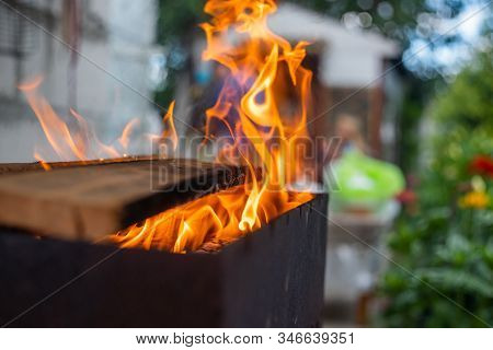 B-b-q Outdoors Background. Kindling Wood Barbecue Outdoors With Open Flame Against The Background Of