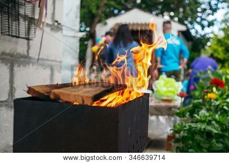 B-b-q Outdoors Background. Kindling Wood Barbecue Outdoors With Open Flame Against The Background Of