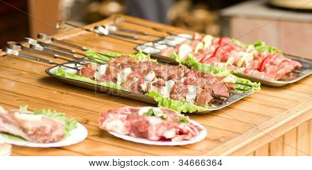 Appetizing weal kebab on skewers with tomatoes, pepper and greens