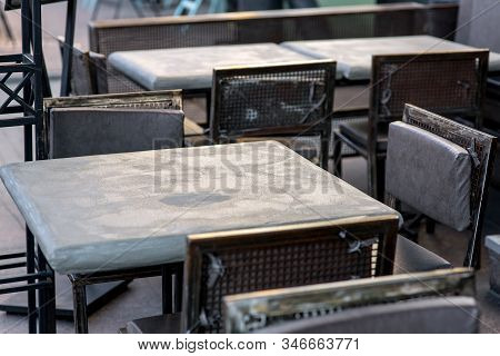 Street Cafe With A Gray Painted Iron Table And Black Iron Chairs With Soft Pillows In A Rough Urban 
