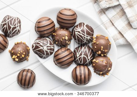 Praline bonbons. Chocolate truffles on plate on white table. Top view.