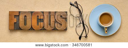 focus word abstract in vintage wooden letterpress printing blocks with a cup of coffee and glasses, productivity, concetration and personal development concept