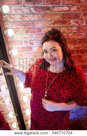 Fat Plump Charming Cute Woman With Black Hair In Red Beautiful Dress In The Room With Mirrow And Red