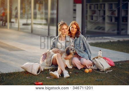 Two Girls Wallking In A Park With A Little Dog
