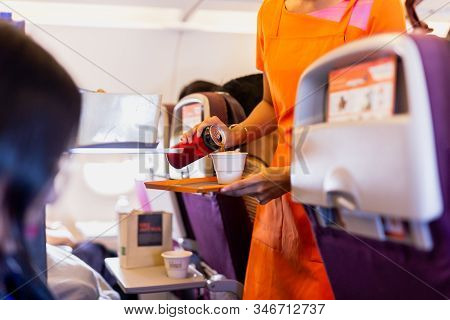 Flight Attendant Serving Drinks To Passengers On Board.
