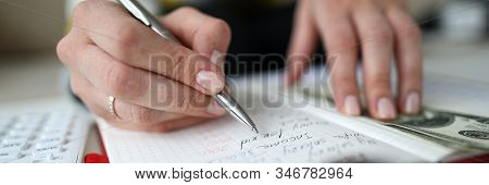 Close-up View Of Woman Managing Domestic Budget And Writing All Down In Notebook. Monthly Income And