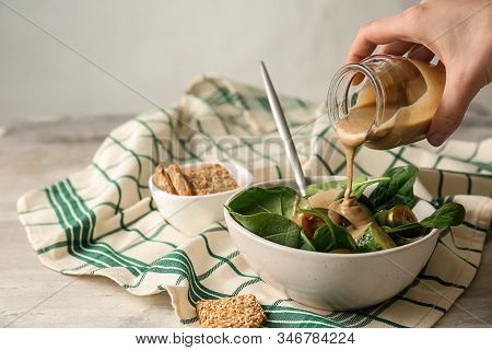 Pouring Of Tasty Tahini From Jar Onto Fresh Vegetables In Bowl