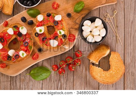 Friselle With Tomatoes And Mozzarella Cheese On Cutting Board.