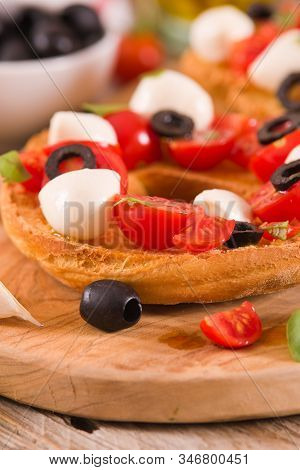 Friselle With Tomatoes And Mozzarella Cheese On Cutting Board.