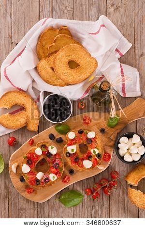 Friselle With Tomatoes And Mozzarella Cheese On Cutting Board.