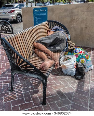 Carlsbad, California, Usa - September 22, 2019: Homeless Person Sleeps On Public Bench At Public Bea