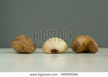 Ugly Vegetables. Potatoes And Onions On A White Wooden Background. The Form Does Not Affect The Tast