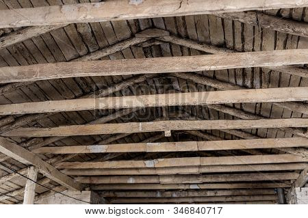 Aged Brown Wooden Timber Beam On Roof Ceiling Inside Old Farm Or Ranch Building Interior. Rural Gabl
