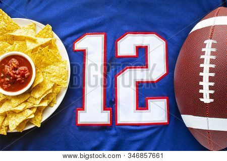 An American Football With Organic Nacho Chips And Mild Salsa On A White Blue Football Jersey With Th