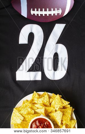 An American Football With Organic Nacho Chips And Mild Salsa On A White Black Football Jersey With T