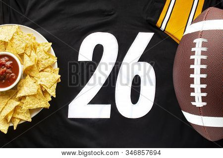 An American Football With Organic Nacho Chips And Mild Salsa On A White Black Football Jersey With T